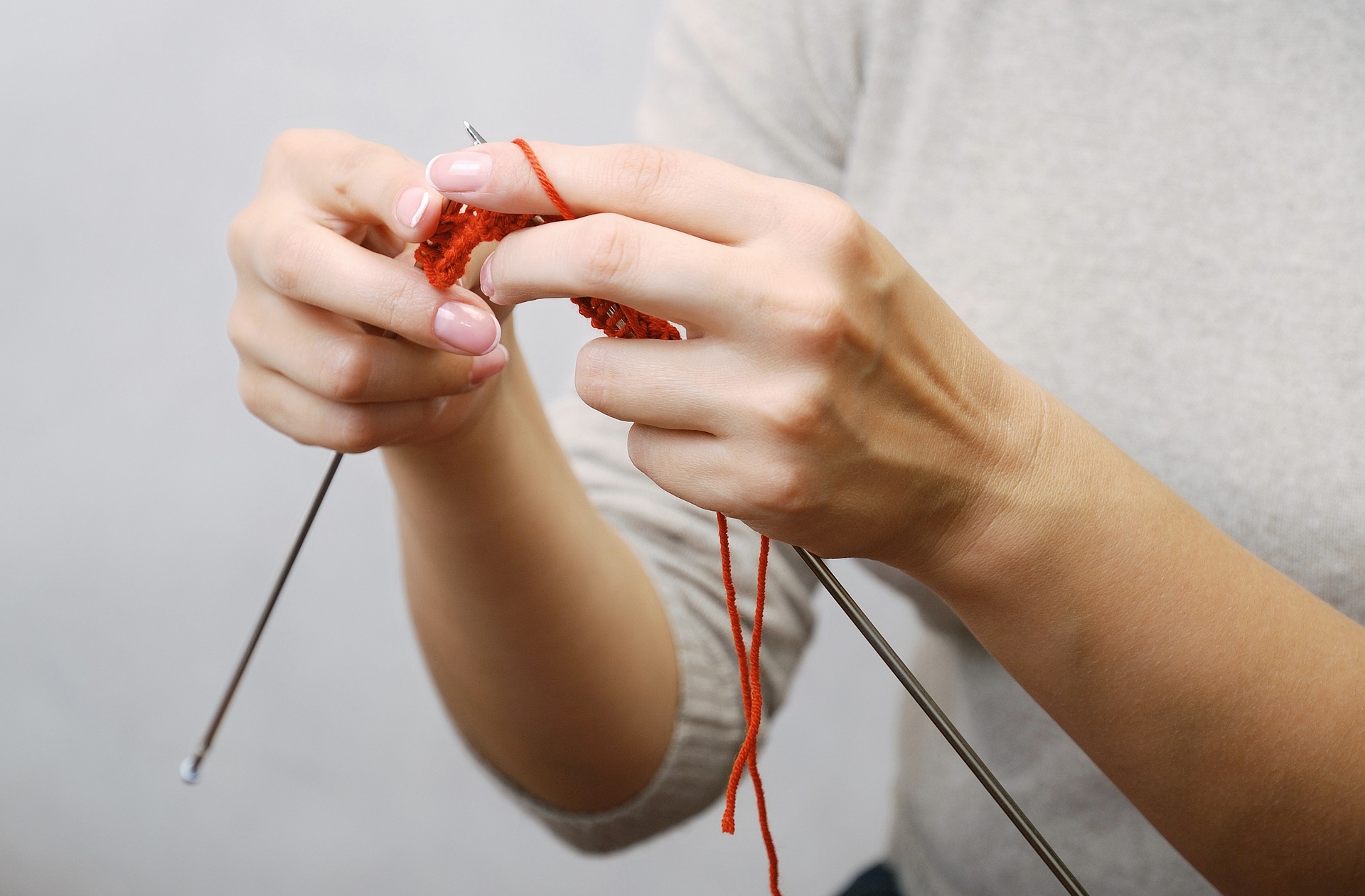 Hands knitting with red wool